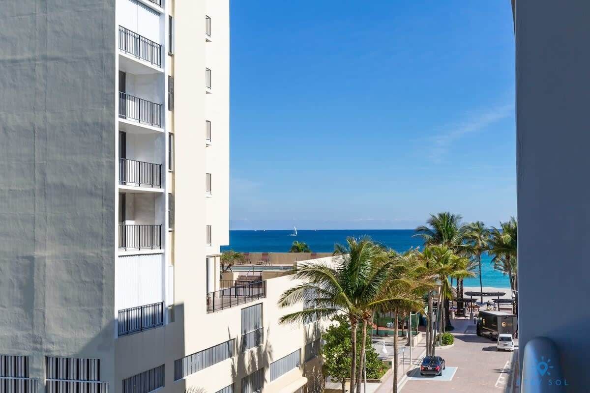 Un immeuble à plusieurs étages doté de balcons donnant sur une plage et l’océan.
