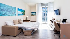 A modern hotel room with a bed, a desk, and a TV.