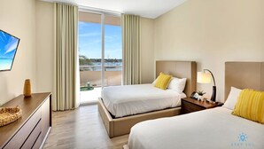 Een hotelkamer met twee bedden, een televisie, een bureau en uitzicht op de stad.