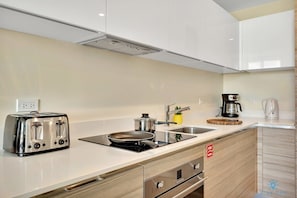 A modern kitchen with a toaster, stove, sink, and coffee maker.