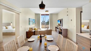 Een moderne hotelkamer met een zithoek, een woongedeelte en een balkon met uitzicht.