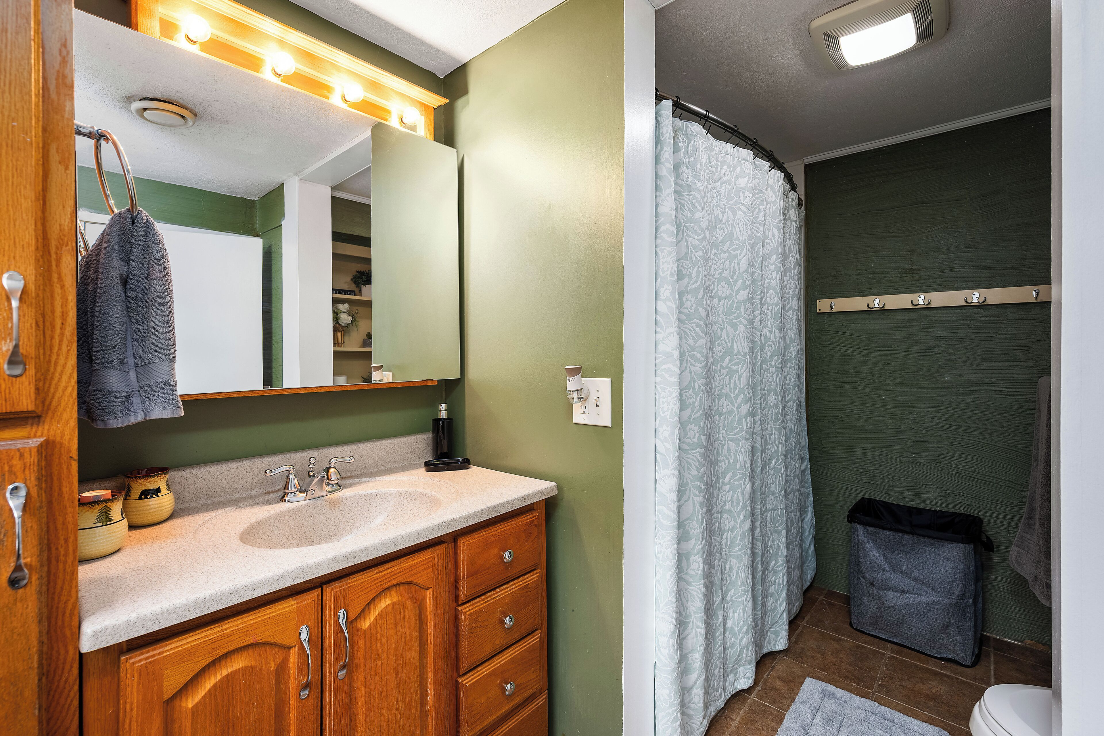 A bathroom with a sink, mirror, and shower curtain.