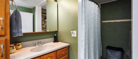 A bathroom with a sink, mirror, and shower curtain.