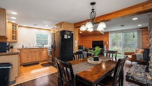 Une cuisine moderne avec des meubles en bois, un réfrigérateur noir et un coin repas comprenant une table et des chaises en bois.