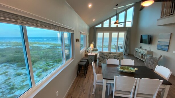 A dining area with a view of the ocean, a ceiling fan, and a television on the wall. - Your Dream Getaway - A Slice of Heaven (St Joe Beach)