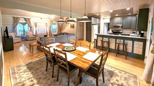 A spacious living area with a wooden dining table, multiple chairs, a sofa, and a kitchen area with a bar counter. - Pet-Friendly Suite in North Georgia Mountains with Kitchen, Dining & Living Room (Dahlonega)