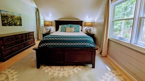A bedroom with a large bed, two bedside tables with lamps, a dresser, a painting on the wall, and a window with curtains. - Pet-Friendly Suite in North Georgia Mountains with Kitchen, Dining & Living Room (Dahlonega)