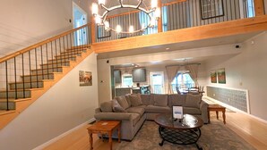 A spacious living area with a large sectional sofa, a wooden coffee table, and a staircase leading to an upper level. - Pet-Friendly Suite in North Georgia Mountains with Kitchen, Dining & Living Room (Dahlonega)