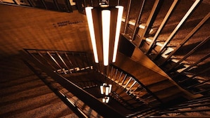 Un escalier en colimaçon surmonté d’un luminaire moderne.