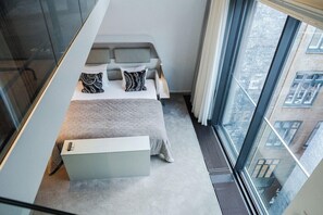 Een moderne slaapkamer met een bed, kussens en een nachtkastje.