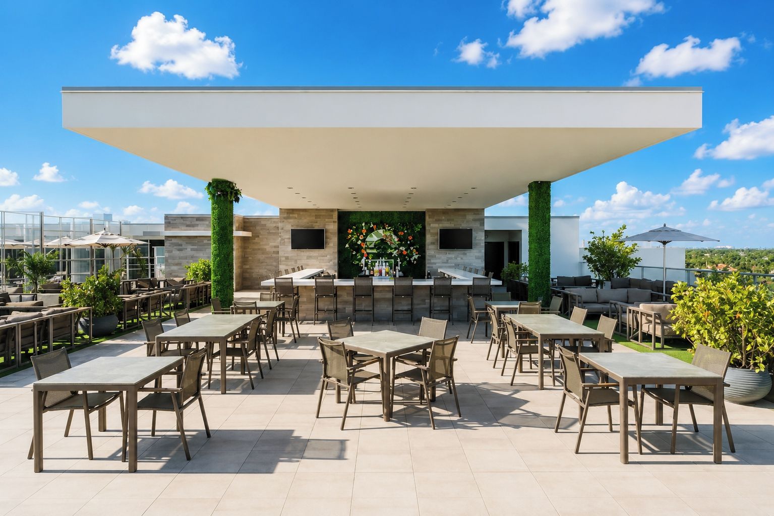 Un patio exterior con varias mesas y sillas, una zona de bar y vistas a la ciudad.