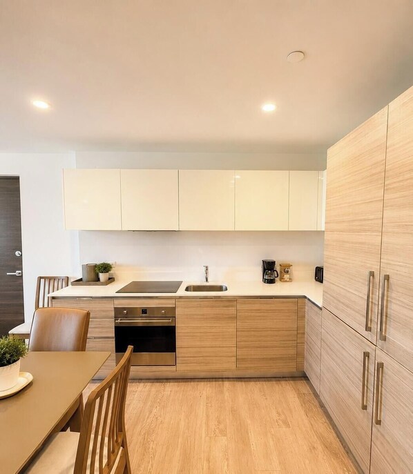 Une cuisine moderne avec des meubles en bois, un four encastré et un coin repas comprenant une table et des chaises.