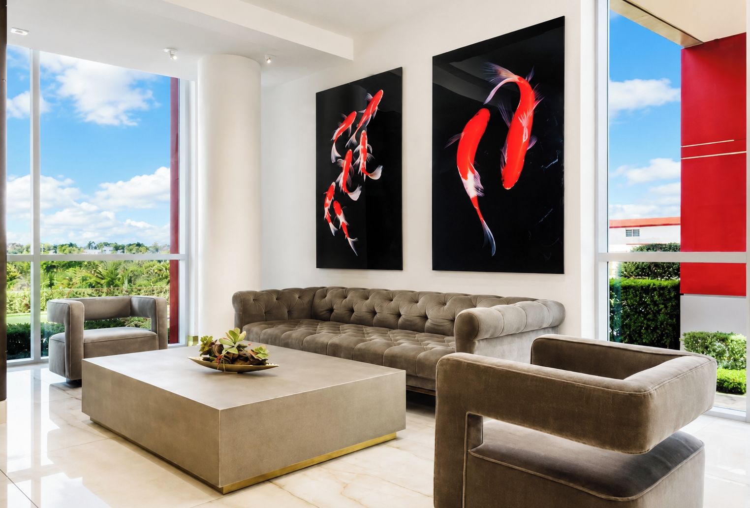 Una sala de estar moderna con un ventanal grande, un sofá gris, una mesa de centro y dos cuadros colgados en la pared con peces koi.