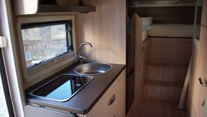A compact kitchenette with a sink, a window, and a small refrigerator. - Wohnmobil PLA Siena 385 (Krostitz OT Kupsal)