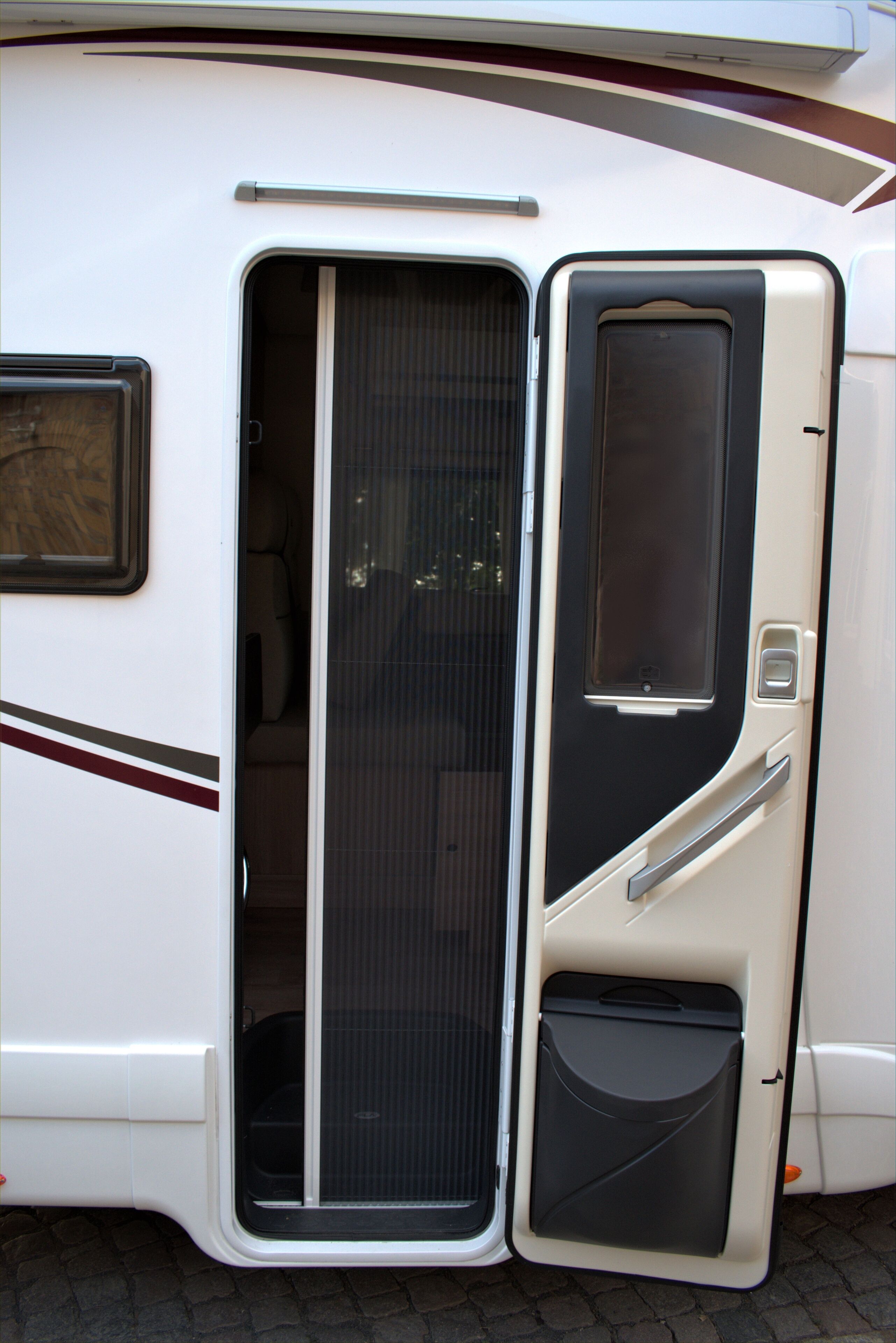 Uma motorhome branca com porta deslizante, uma pequena janela e compartimento de armazenamento.