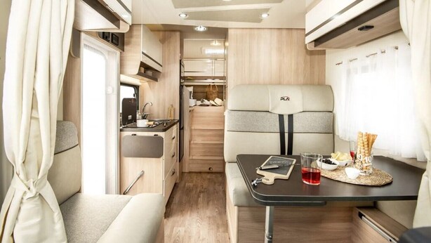 A compact RV interior with a kitchenette, a dining area, and a seating space. - Wohnmobil PLA Siena 385 (Krostitz OT Kupsal)