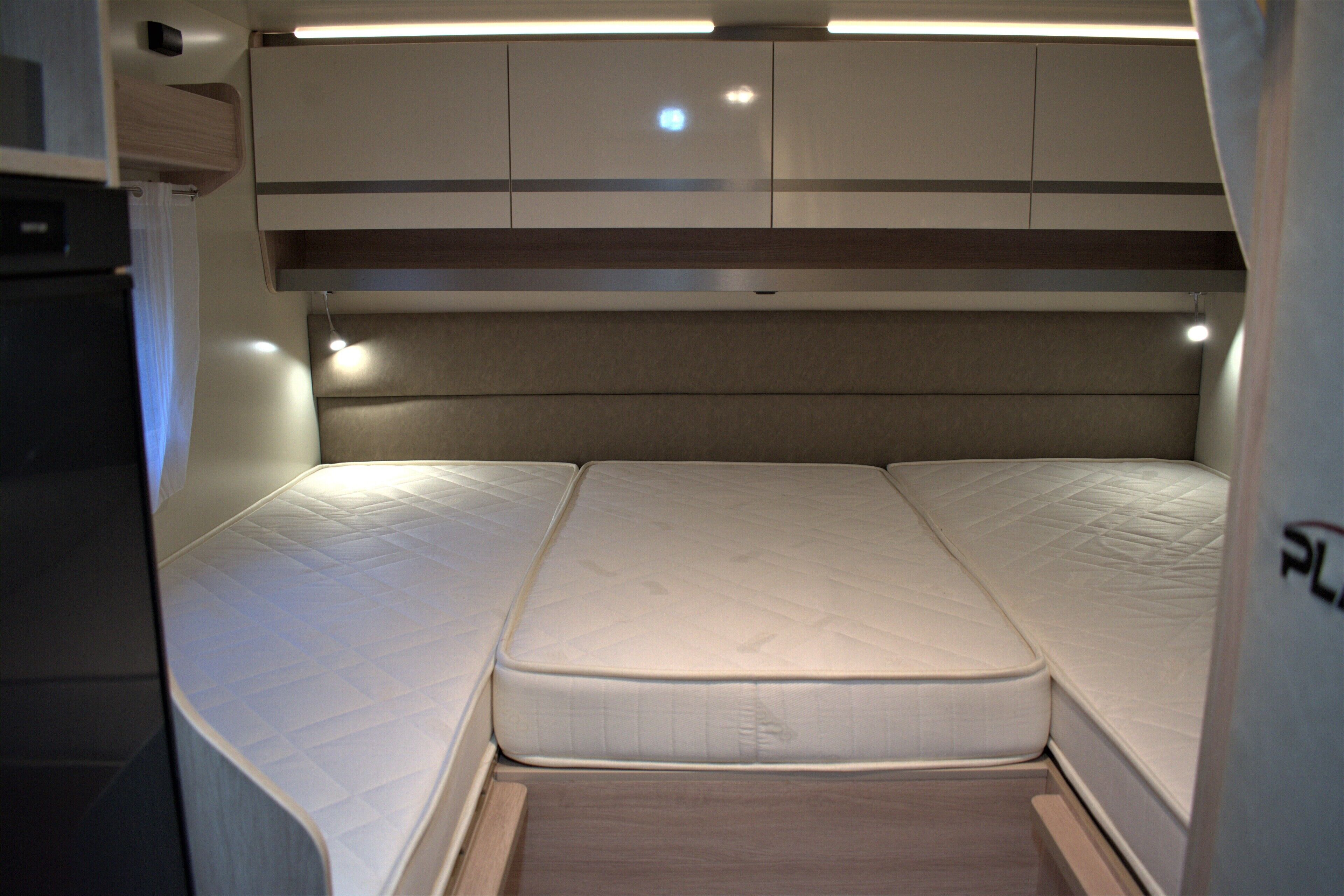 A compact bed with a headboard and a storage cabinet above it.