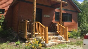 A wooden lodge with a porch, stone steps, and a sign requesting guests to remove ski boots. - Work Remote in Paradise on North Creek (North Creek)