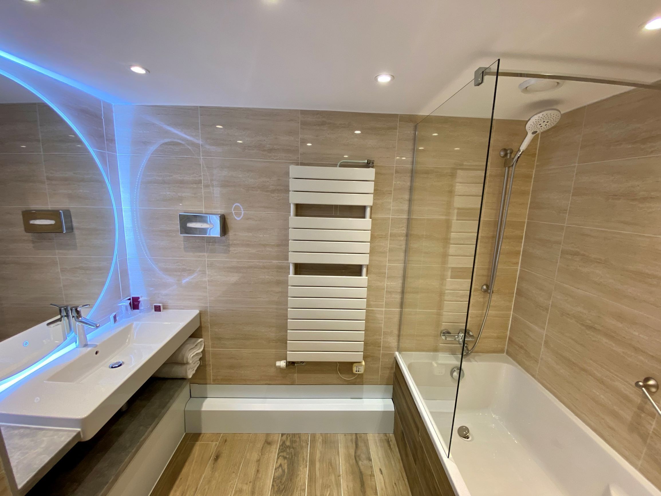 Une salle de bain moderne dotée d’une douche à parois de verre, d’un banc intégré et d’un meuble-lavabo avec un miroir.