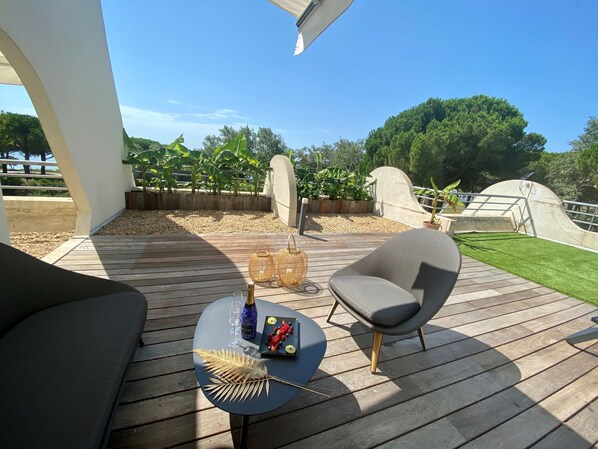 A wooden deck with a table set for two, a chair, and a bottle of champagne. - Golf Hôtel (La Grande-Motte)