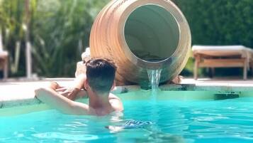 Une personne se détend dans une piscine, près d’un grand tonneau en bois.