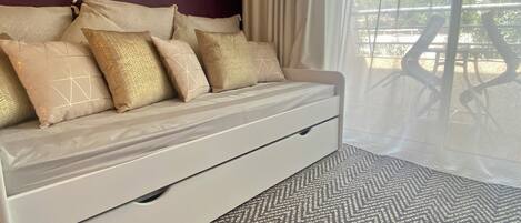 A bed with a headboard, multiple pillows, and a bedside table.