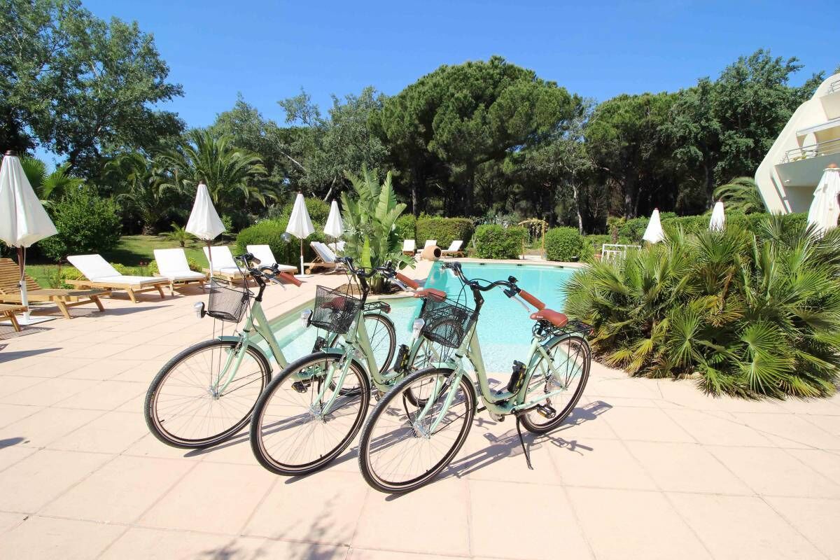 A poolside area with bicycles, lounge chairs, and umbrellas.