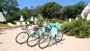 A poolside area with bicycles, lounge chairs, and umbrellas.