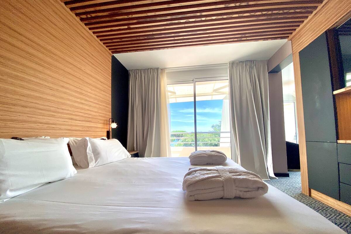 Une chambre d’hôtel avec un grand lit, un plafond en bois et une vue sur l’extérieur.