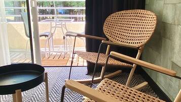 A room with wicker chairs and a small table, a patterned carpet, and a view of an outdoor patio area.