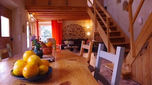 A wooden interior with a dining table, oranges, and a staircase.