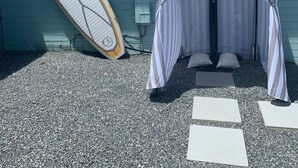 Uma casa de praia com uma tenda listrada e uma prancha de surf encostada na parede.
