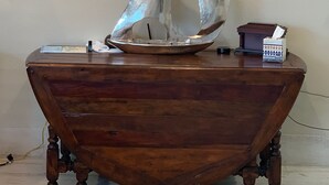 Uma mesa de madeira com um modelo de veleiro de metal e uma placa acima com a inscrição 'BEACHHOUSE'.