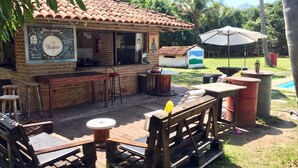 Ein Außenbereich mit einer Holzterrasse, einer Bar aus Backstein und einem kleinen Pool.