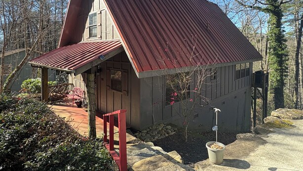 A small, rustic cabin with a steeply pitched roof and a red metal roof. - Red Top Treehouse Cabin in Mirror Lake and minutes to downtown-Dog Friendly! (Highlands)