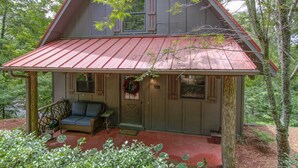 A cabin with a porch, a wicker sofa, and a welcome wreath. - Red Top Treehouse Cabin in Mirror Lake and minutes to downtown-Dog Friendly! (Highlands)