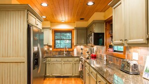 A kitchen with wooden cabinets, granite countertops, and stainless steel appliances. - Red Top Treehouse Cabin in Mirror Lake and minutes to downtown-Dog Friendly! (Highlands)