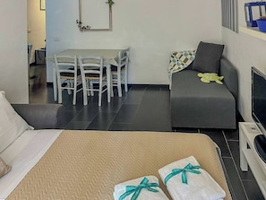 Une chambre d’hôtel avec un lit, un canapé, une télévision et un bureau avec des chaises.