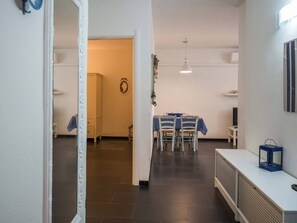 A room with a dining table, chairs, a white cabinet, and a television. - Sciacchetrà Ground Floor Apartment with AC and Patio (Monterosso al Mare)