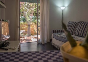 Une chambre à coucher comprenant un lit, un bureau, une lampe et donnant sur un espace extérieur aménagé avec une table et des chaises.