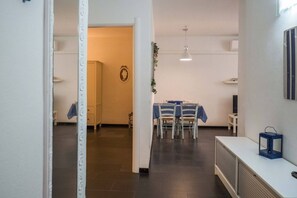Un couloir menant à une salle à manger équipée d’une table et de chaises, d’un radiateur et d’un luminaire fixé au mur.