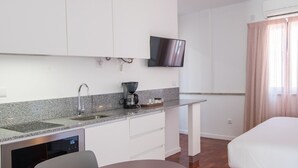 Cuina compacta amb rentaplats integrat, màquina de cafè i televisió de pantalla plana penjada sobre la barra.