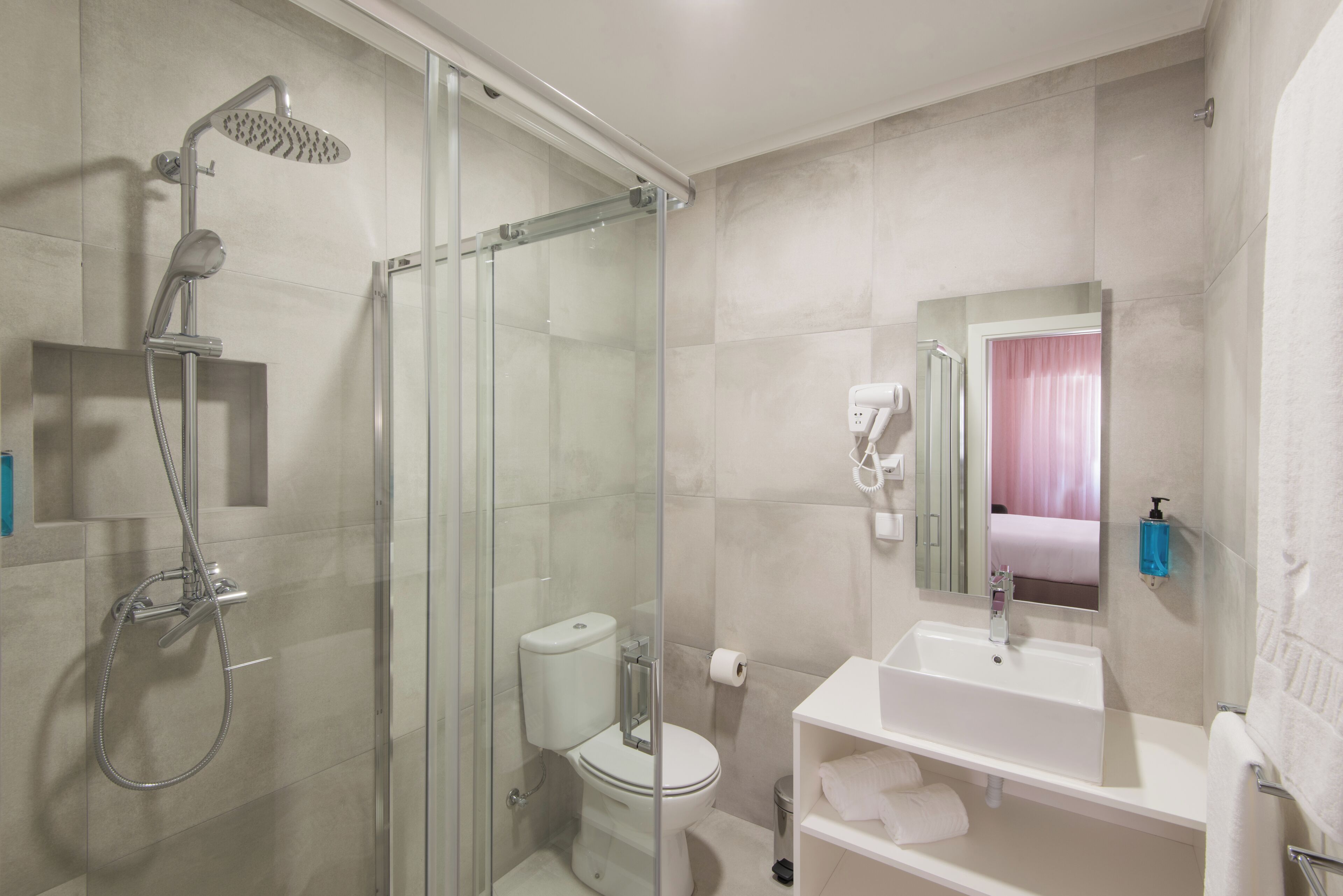 A modern bathroom with a glass-enclosed shower, a toilet, a sink, and a mirror.