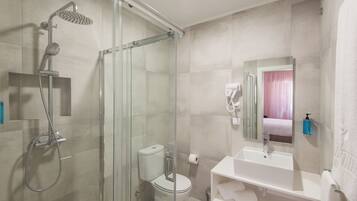 A modern bathroom with a glass-enclosed shower, a toilet, a sink, and a mirror.