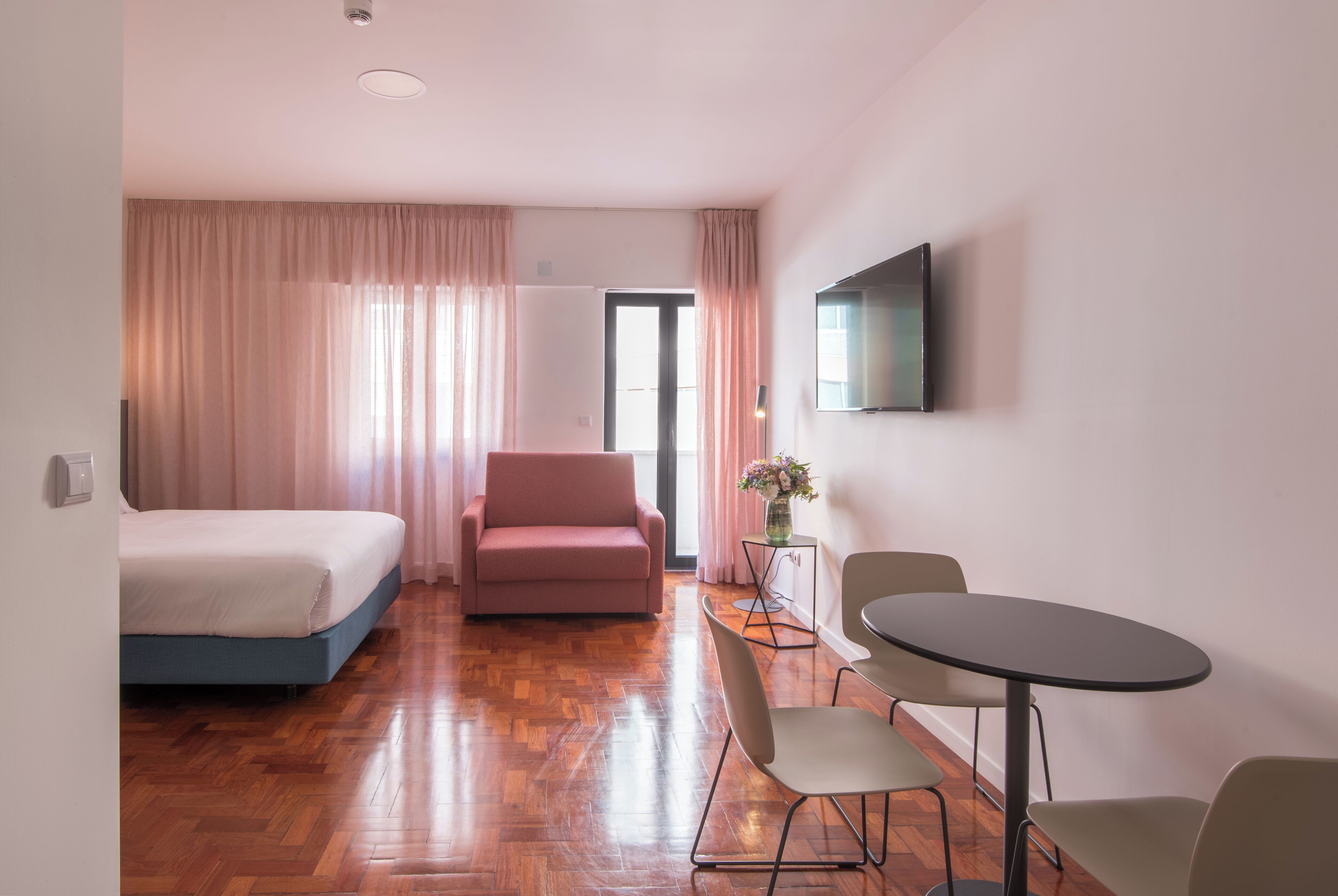 Una habitación de hotel con cama, sofá, mesa de comedor y televisor.