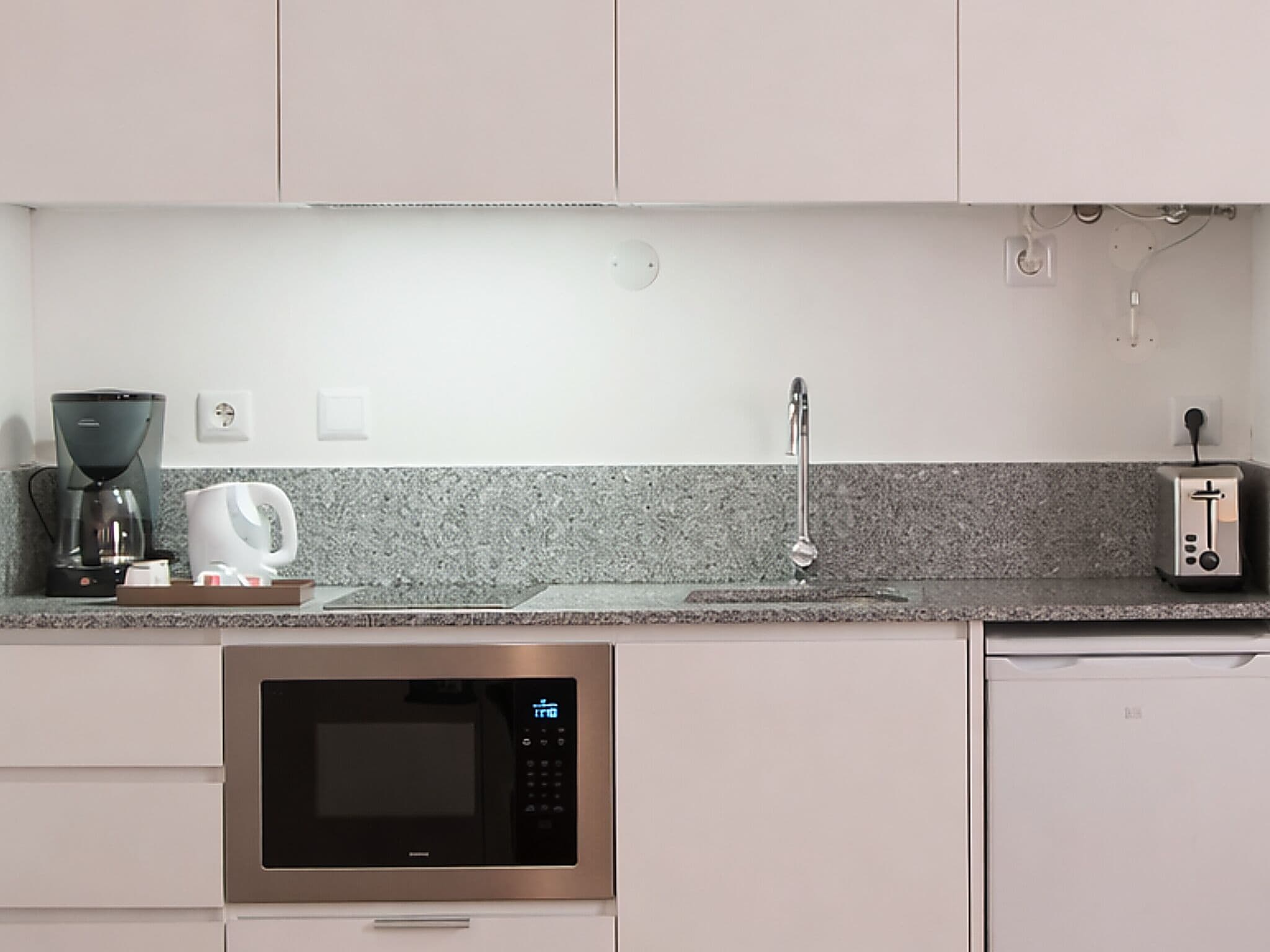 A modern kitchen with a built-in microwave, coffee maker, and toaster.