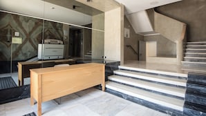 Rebedor modern d'hotel amb una banca de fusta, una paret de vidre i una escala.
