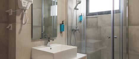 A modern bathroom with a glass-enclosed shower, a large mirror, and a white vanity.