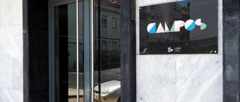 Ingresso di un edificio con un cartello per 'Lisbon Serviced Apartments' e il logo di 'CAPOS'.