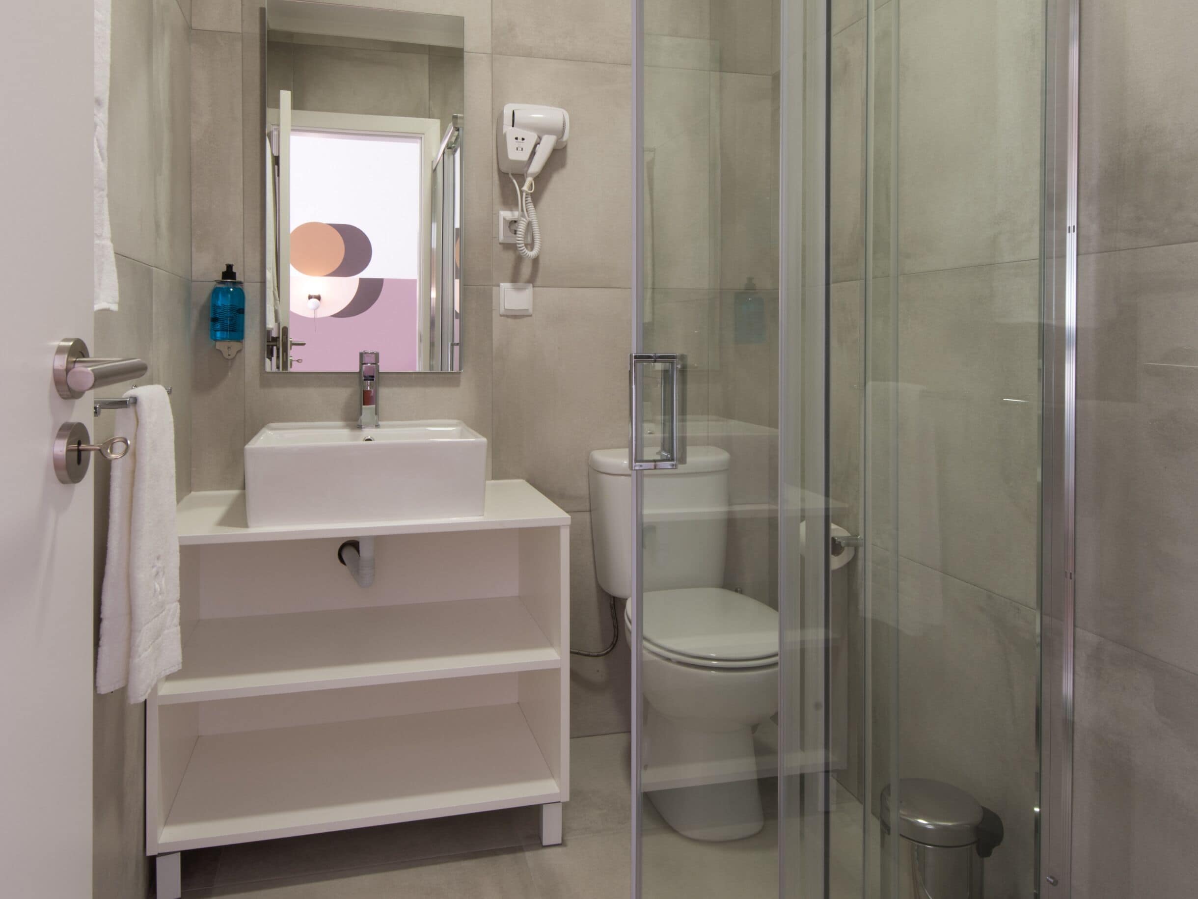 A modern bathroom with a glass-enclosed shower, a white sink, and a toilet.
